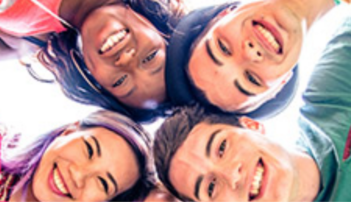 Smiling young people in a huddle looking down at the camera